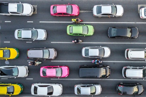 Four lanes of traffic on a motorway viewed from above.